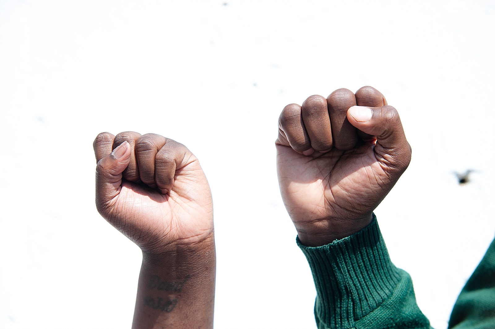 Close of two Black people's hands in Black Power symbol