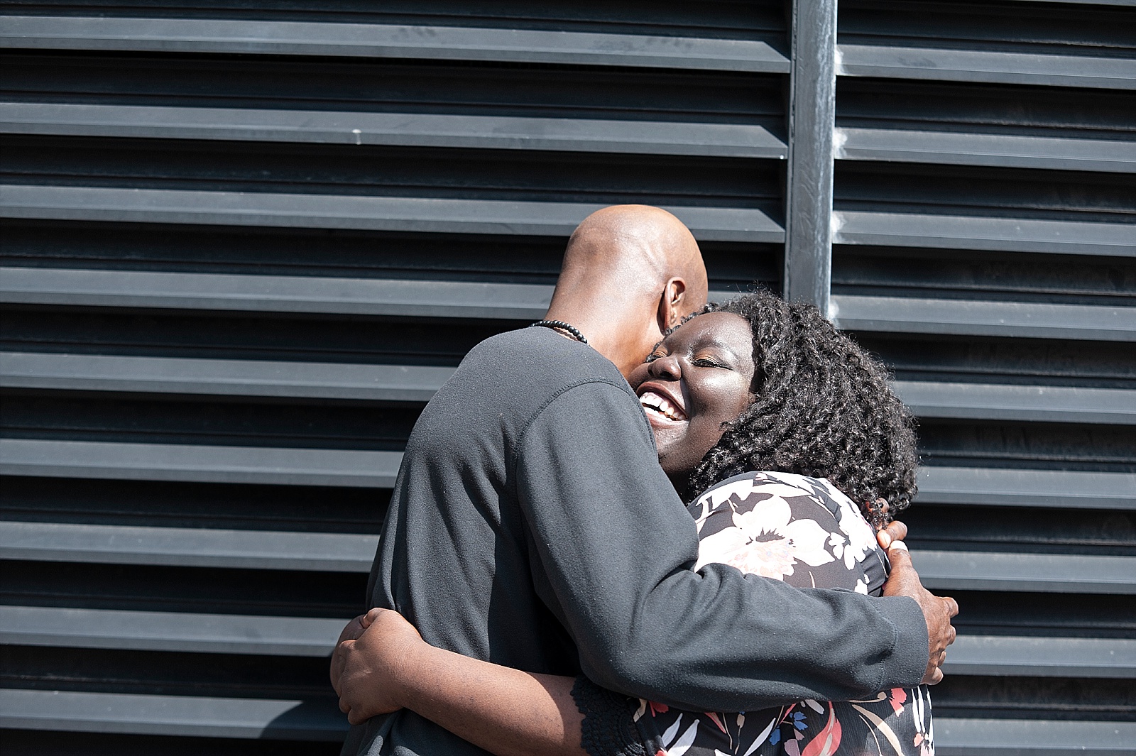 Smiling Black woman hugs Black man